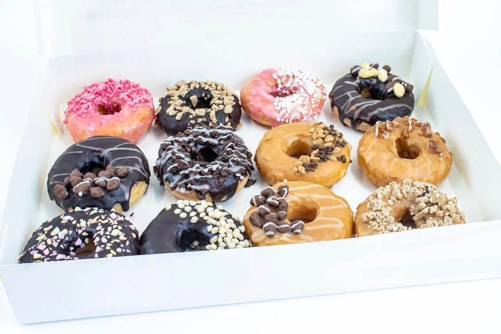 Box of 12 mixed donuts with inclusions on white background