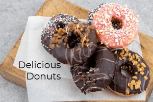 Delicious Donuts header image with multiple inclusion topped donuts piled on cuttingboard and baking paper-grey bg