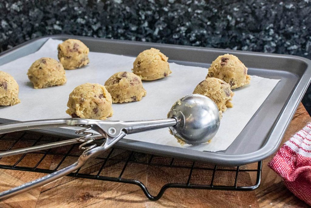 Fudge Chunk Biscuit dough on tray in kitchen with portion scoop