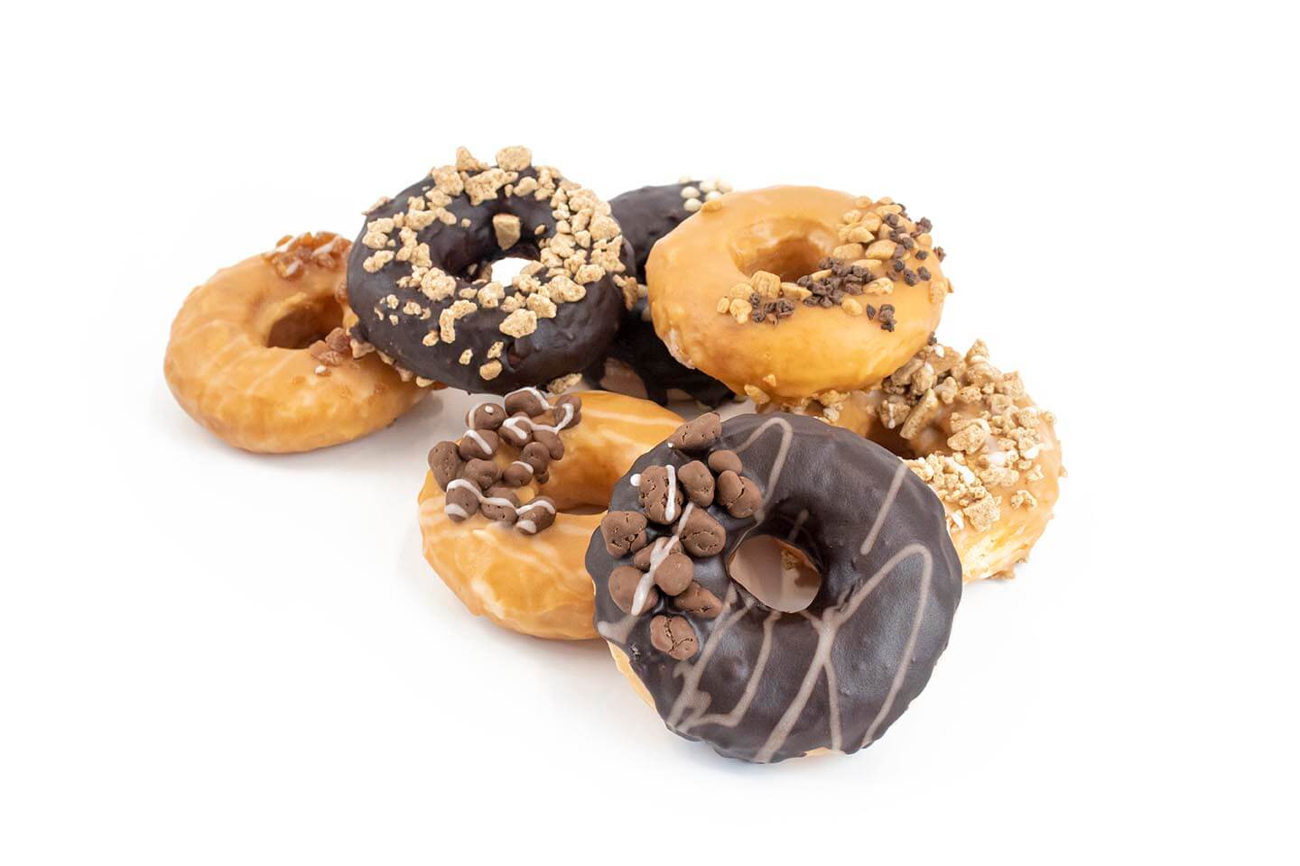 pile of inclusion topped donuts with caramel and chocolate flavour focus on white background